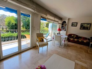 A spacious living area with a sliding glass door leading to a balcony, a white table, a red lamp, and a sofa. - Swimming pool, 3 bedrooms, baby-friendly (Toulon)