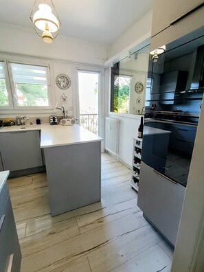 A modern kitchen with a central island, built-in appliances, and large windows. - Swimming pool, 3 bedrooms, baby-friendly (Toulon)