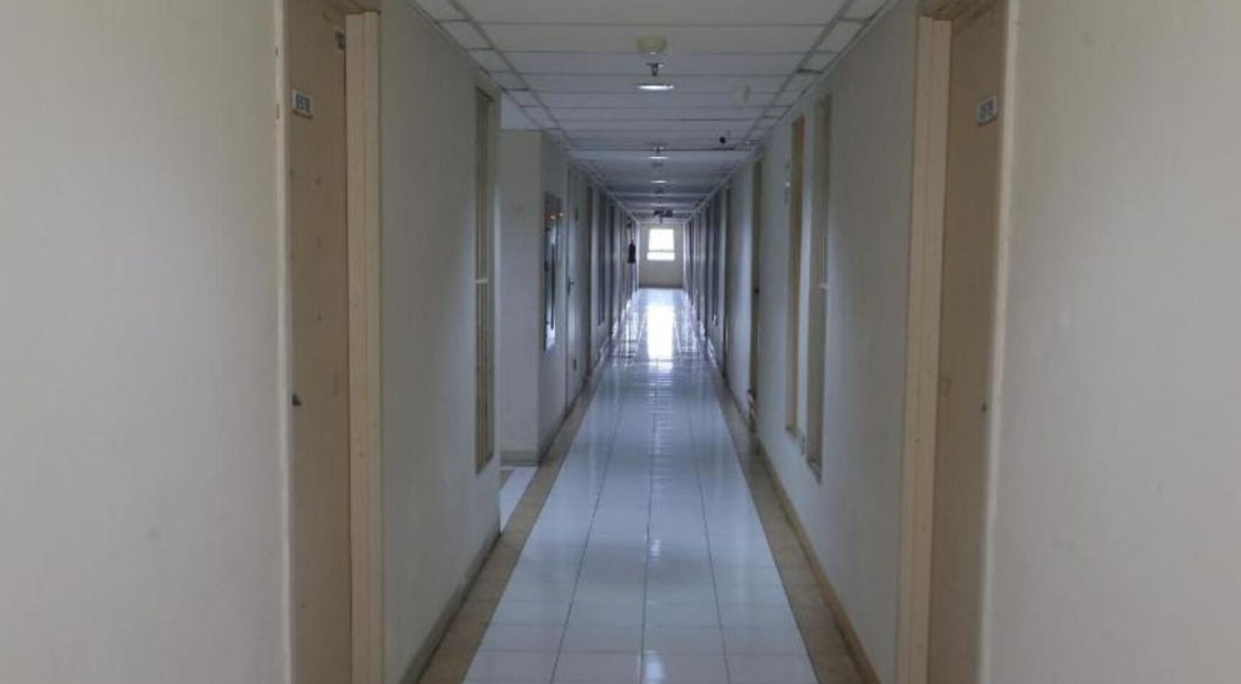 A long, narrow hallway with doors on both sides, leading to rooms.