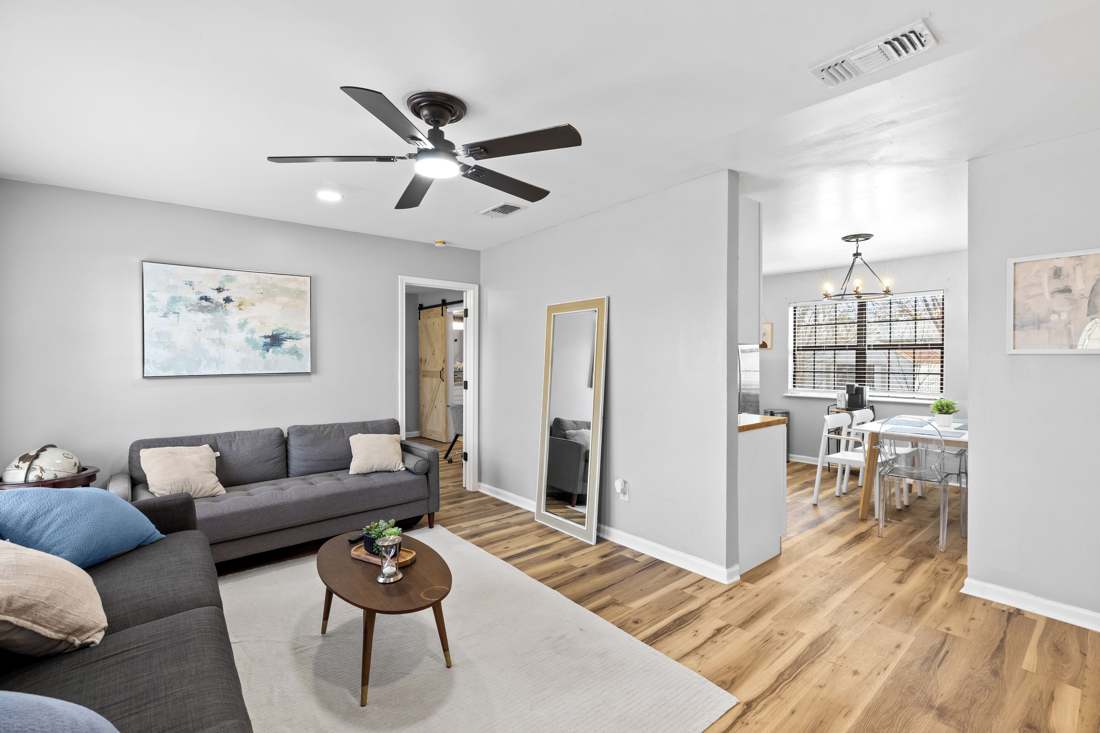 A modern living room with a gray sofa, a coffee table, and a ceiling fan.