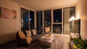 Ein modernes Wohnzimmer mit einer Couch, einem Couchtisch und einem großen Fenster mit Blick auf die Stadt.