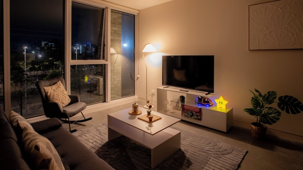 Ein Wohnzimmer mit einer Couch, einem Couchtisch, einem Fernseher und einer Pflanze.