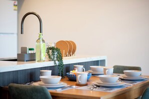 A dining area with a kitchen counter, a sink, and various dishes and utensils. - Stadium View (Lidcombe)