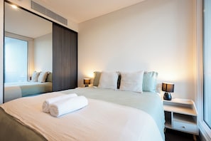 A modern hotel room with a large bed, bedside lamps, a nightstand, and a mirror. - Stadium View (Lidcombe)