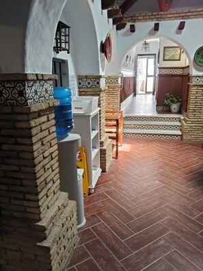A hallway with a tiled floor, a water dispenser, and a brick wall.