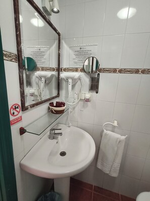 A bathroom with a sink, mirror, towel rack, and a no-drinking sign. - Hostal Casa Francisco el de siempre (Vejer de la Frontera)