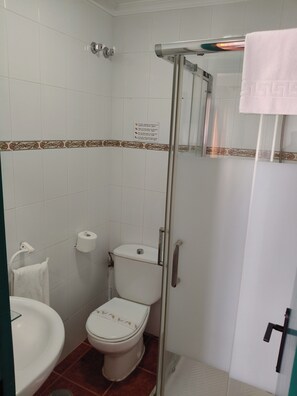 Un baño con inodoro, lavamanos y cabina de ducha de vidrio.