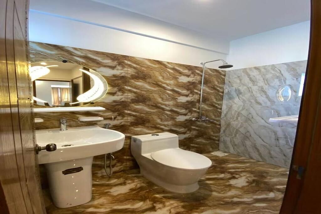 Une salle de bain avec un meuble-lavabo en marbre, des toilettes et un espace douche.