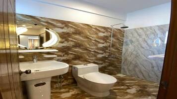 A bathroom with a marble vanity, a toilet, and a shower area.