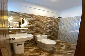 Un baño con tocador de mármol, inodoro y zona de ducha.