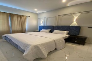 Un dormitorio con una cama grande, una mesita de noche y una lámpara de pared.