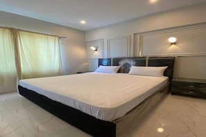 Una habitación de hotel con una cama grande, dos lámparas de noche y una ventana con cortinas.