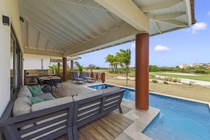 A covered outdoor area with a pool, lounge chairs, and a barbecue. - Villa Zaya Blue Bay Private Pool Golf View (Sint Michiel)