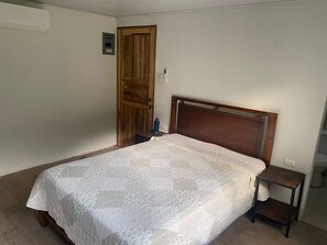Ein Schlafzimmer mit einem hölzernen Bettgestell, einem Nachttisch und einer Tür.