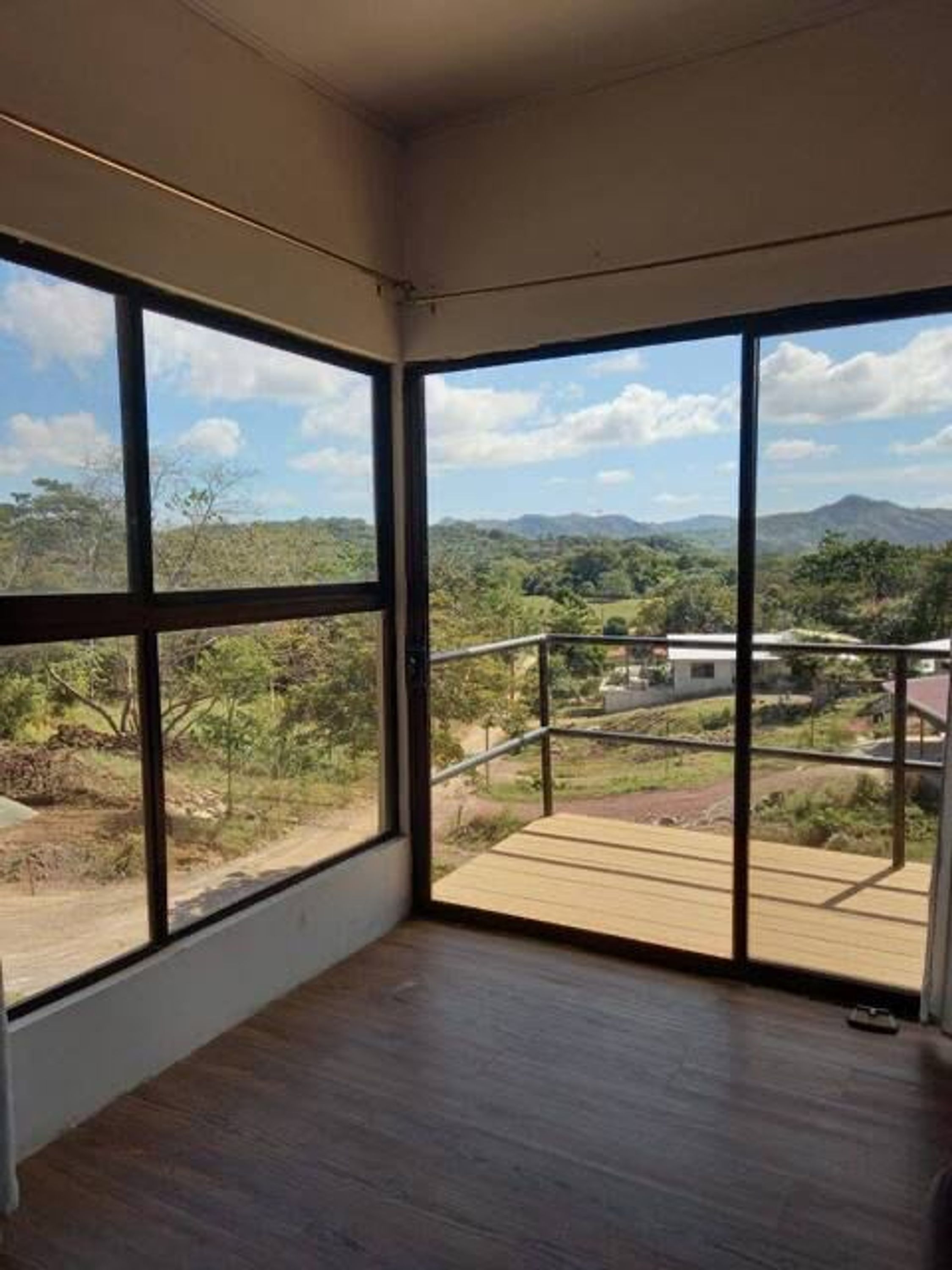 Ein Zimmer mit großen Fenstern und Blick auf eine gebirgige Landschaft.