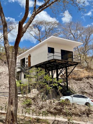 A modern two-story house with a flat roof, a balcony, and a car parked in front. - w Cozy 2BR Near Playa Grande w Mountain Views (Cabo Velas)