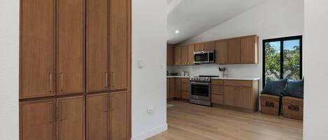A modern kitchen with wooden cabinets, a microwave, an oven, and a large window.