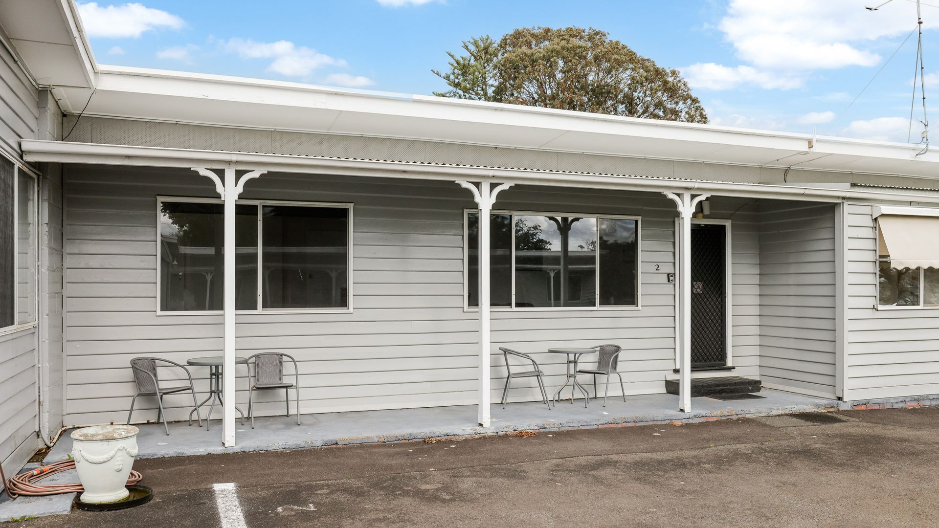 A single-story building with a covered porch, two windows, and a door.