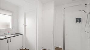 Uma casa de banho moderna com chuveiro, sanita e lavatório.