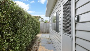 A residential property with a wooden fence, a pathway leading to the house, and a security gate.