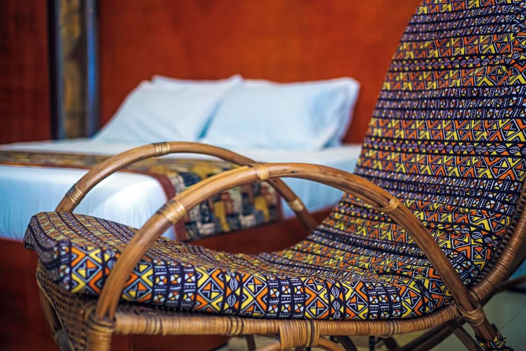 A wicker chair with a patterned cushion in a room with a bed and pillows.