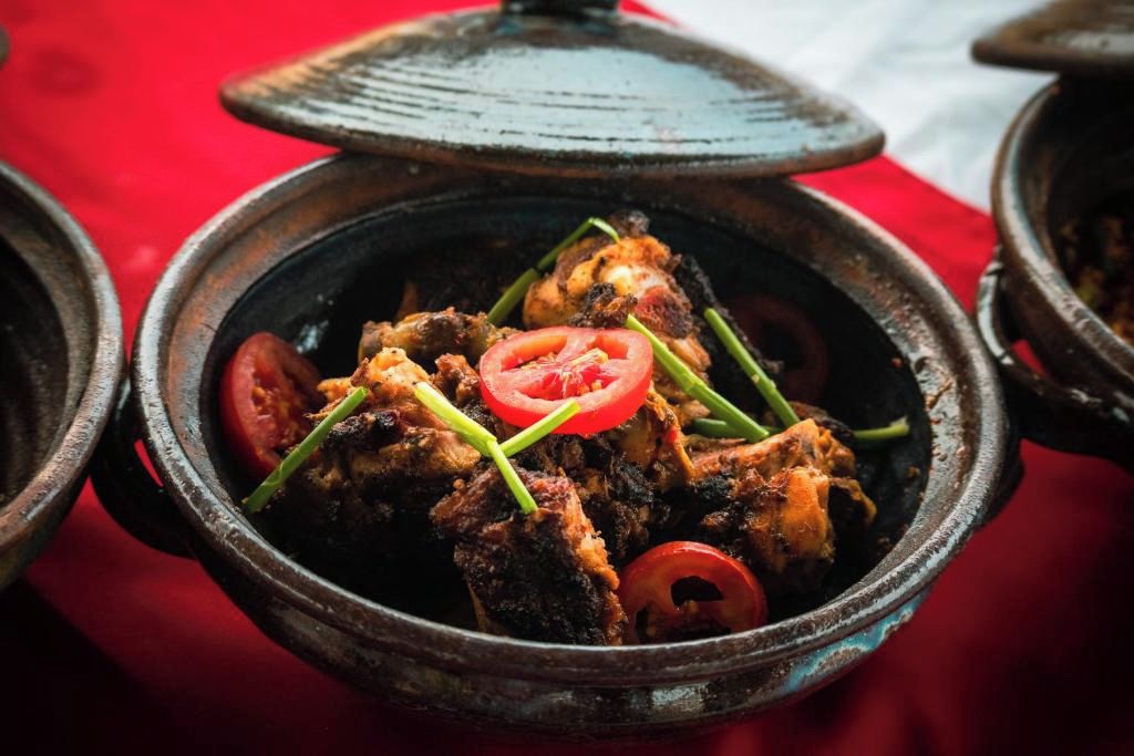 A traditional clay pot with a lid, containing a dish with meat and vegetables.