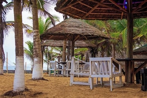 Une plage avec des parasols en chaume et des chaises en bois.