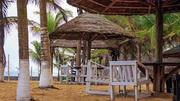 A beach with thatched umbrellas and wooden chairs.