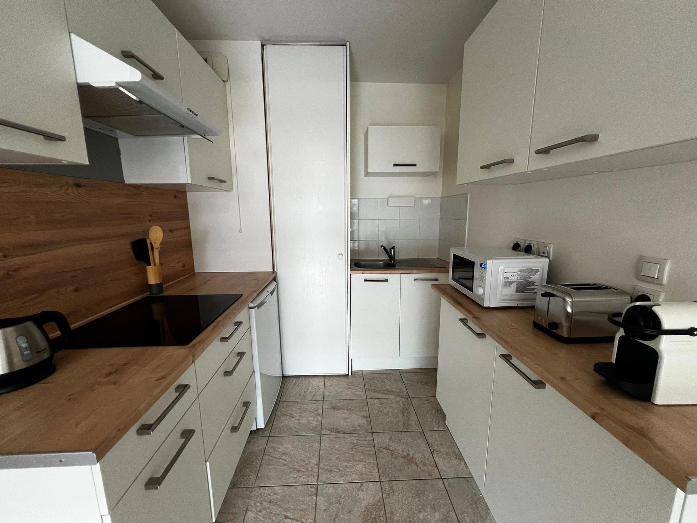 Una cocina moderna con armarios blancos, encimera de madera, microondas, tostadora y un lavabo.