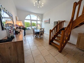 Ein Essbereich mit Tisch und Stühlen, eine Treppe und ein großes Fenster mit Ausblick.