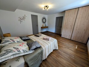 A bedroom with a bed, a bedside table, a wardrobe, and a mirror on the wall. - Spacious house in the heart of nature - 6 guests (Écromagny)