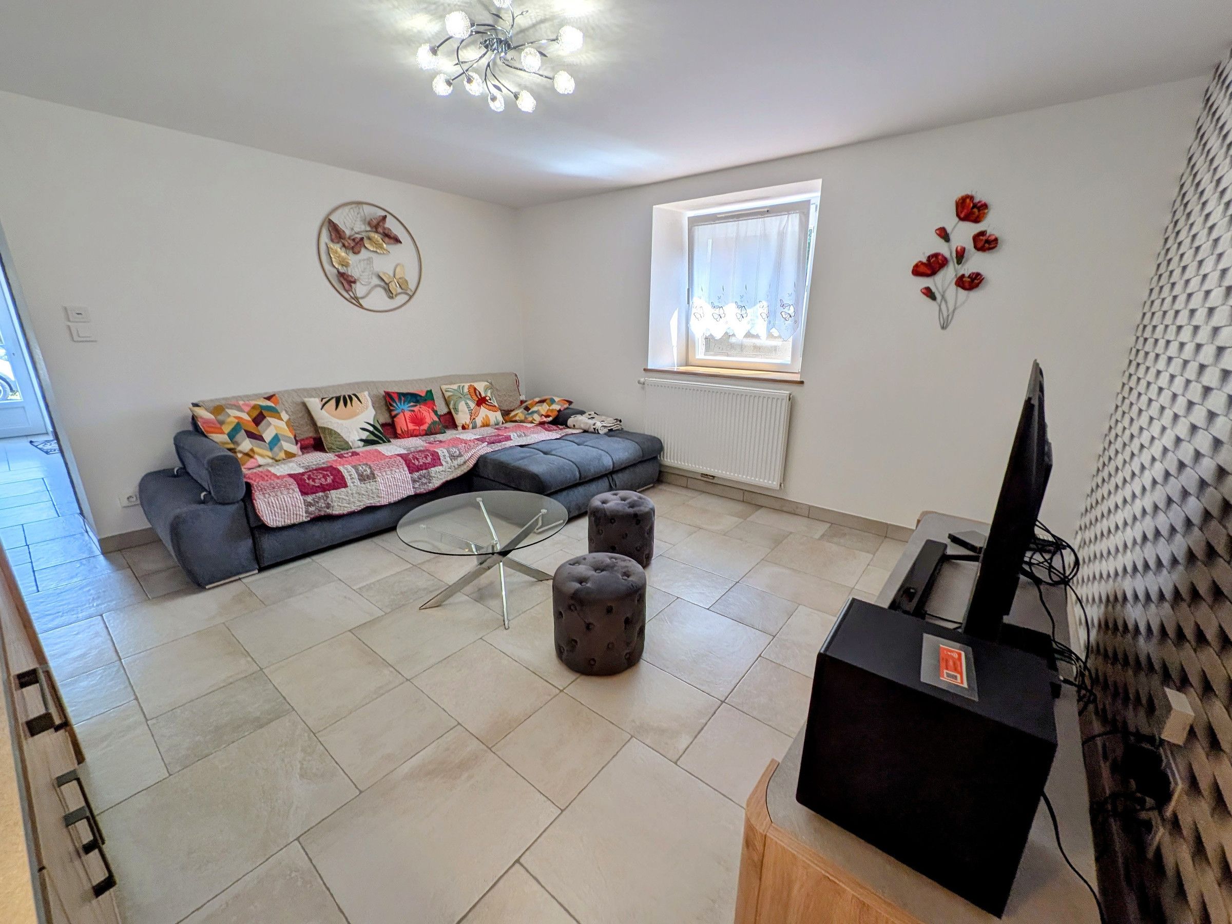 A living room with a sofa, a glass coffee table, and a television on a wooden stand.