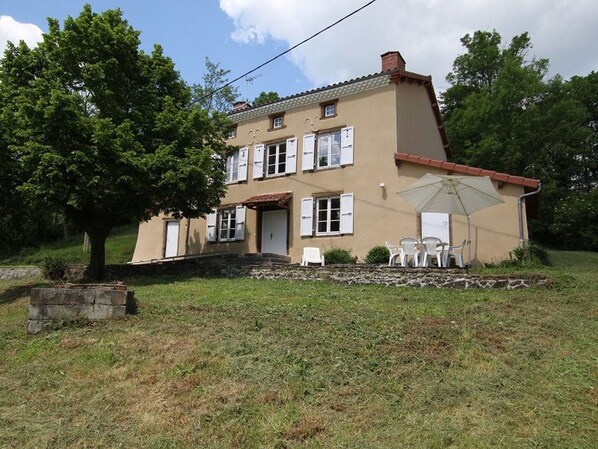 A two-story house with a patio area featuring outdoor furniture. - Spacious house in nature - 10 guests (Mazerat-Aurouze)