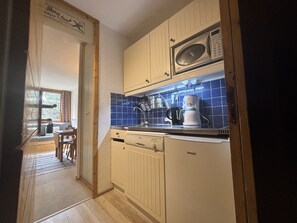 A compact kitchen with a microwave, coffee maker, and a sink. - Bright studio with terrace - 4 guests (La Plagne Montchavin Les Coches)