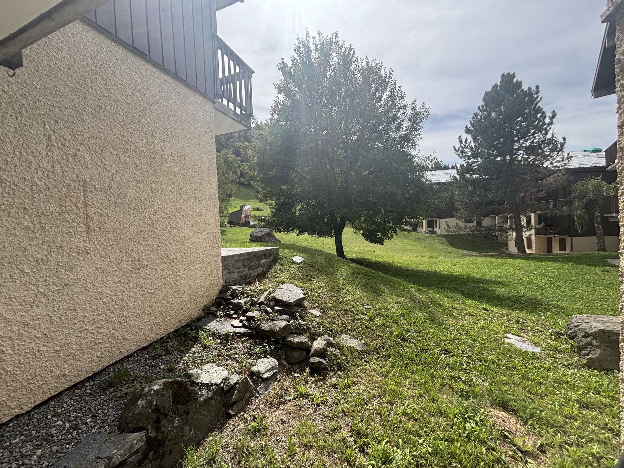 A building with a stone facade, a grassy yard, and trees.