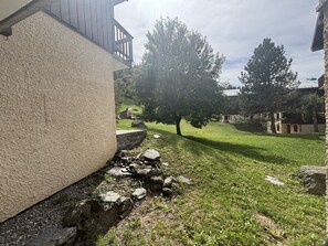 Um edifício com fachada de pedra, gramado e árvores.