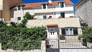 A two-story building with a tiled roof, a gated entrance, and a stone wall with greenery. - MARIO-50m from the beach,big terrace with sea view. FREE PARKING (Stobreč)