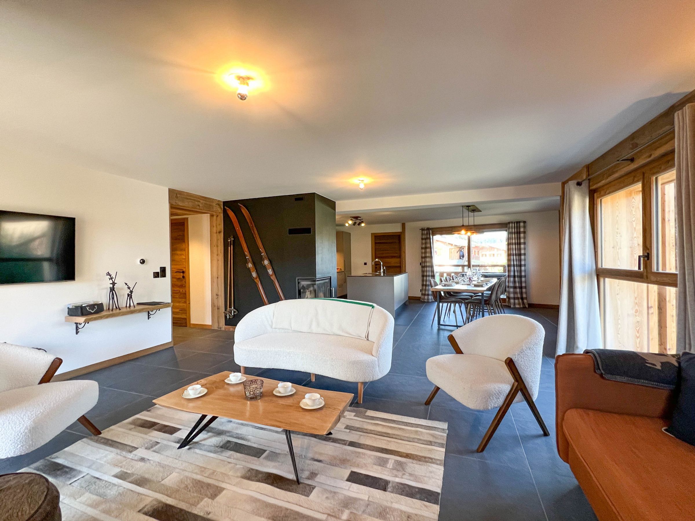 A spacious living area with a sofa, chairs, a coffee table, and a television mounted on the wall.