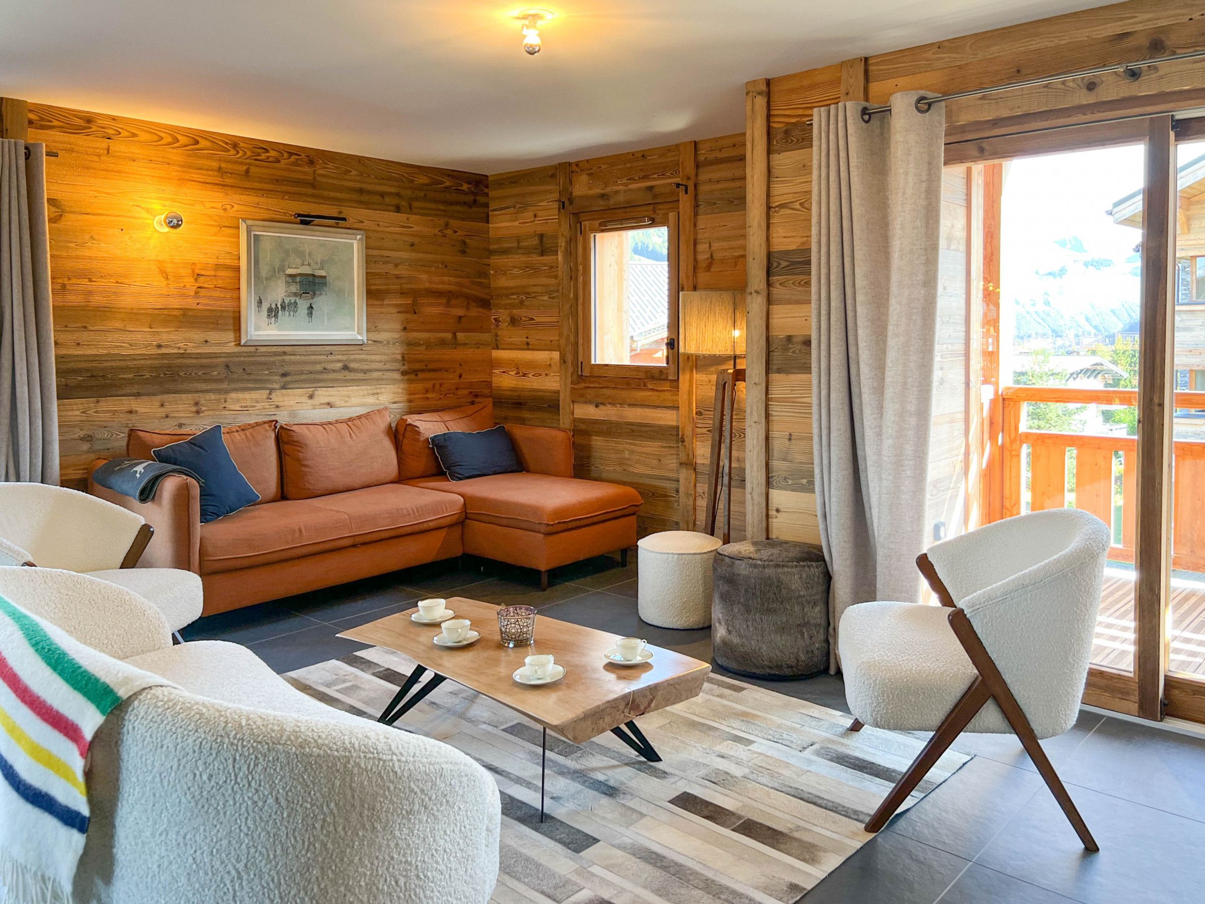 A cozy cabin interior with a sectional sofa, a round coffee table, and a white armchair.