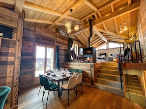 Ein Holzinnenraum mit Essbereich, Kamin und Treppe.