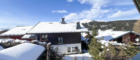 A snow-covered landscape with a wooden cabin and a house with a sloped roof.