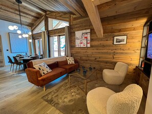 A cozy living room with a wooden interior, a glass coffee table, a sofa, and a chair. - Apartment in Les Gets - 2 bedrooms, 6 guests, Private garage (Les Gets)