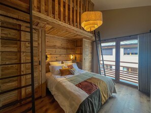 A wooden cabin-style bedroom with a loft bed, a ladder, and a large window with a view. - Spacious apartment Les Gets, 3 beds, WiFi, parking included (Les Gets)
