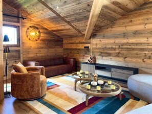A cozy cabin interior with a wooden ceiling, a leather sofa, a round coffee table with candles, and a rustic decor. - Spacious apartment Les Gets, 3 beds, WiFi, parking included (Les Gets)