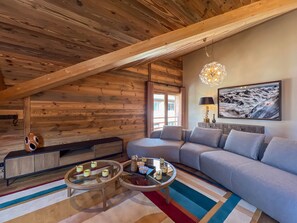 A cozy living room with a wooden ceiling, a sofa, a coffee table, and a painting on the wall. - Spacious apartment Les Gets, 3 beds, WiFi, parking included (Les Gets)