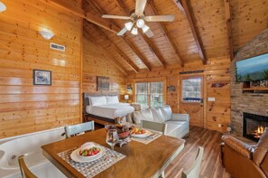 Interior acogedor de una cabaña con detalles de madera, una chimenea, comedor y una cama.