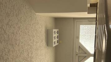 Eine Treppe mit einer strukturierten Wand, eine Tür mit einer satinierten Glasscheibe und ein Lichtschalter an der Wand.