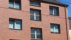 A multi-story brick building with a garage door, a covered entrance, and a traffic light. - Vrbo Property (Essen)