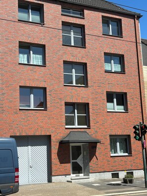 A multi-story brick building with a garage door, a covered entrance, and a traffic light. - Vrbo Property (Essen)