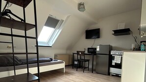 A compact room with a bunk bed, kitchenette, and a small dining area. - Vrbo Property (Essen)